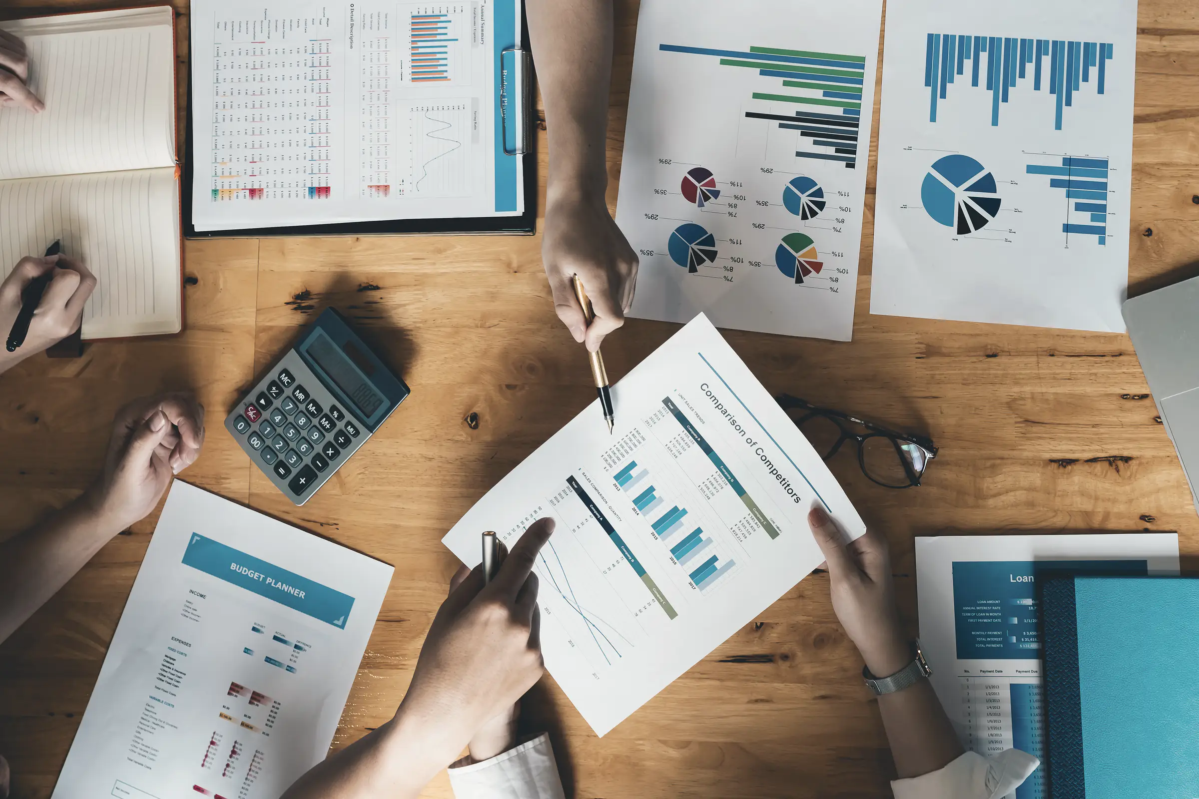 A team working through reports and charts at a shared desk