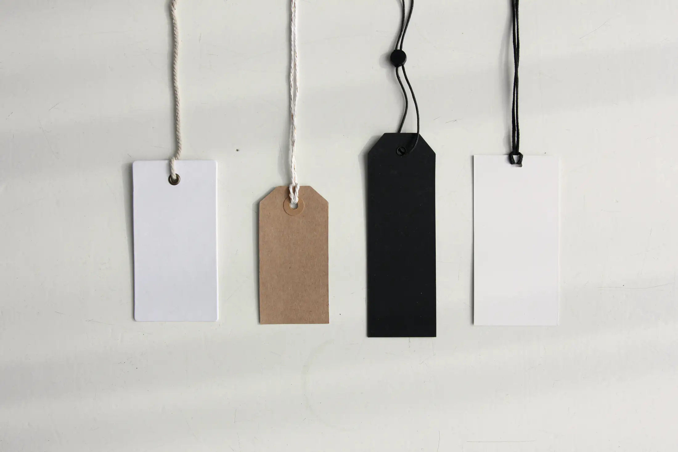 Four blank paper price tags hanging in a row